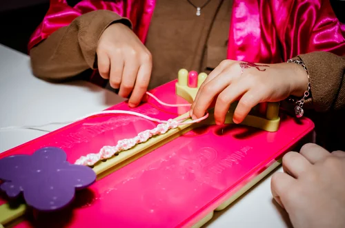 Child crafting handmade item at pink themed party table