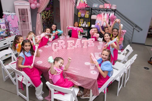 Girls posing behind "create" sign at party