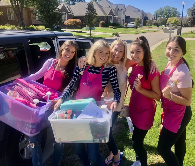 Girls posing with gift bags outside decorated car