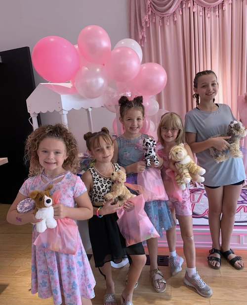 Kids posing with dolls at pink birthday party